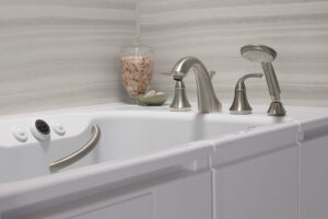 A walk-in tub system with silver fixtures and bath salts in the corner