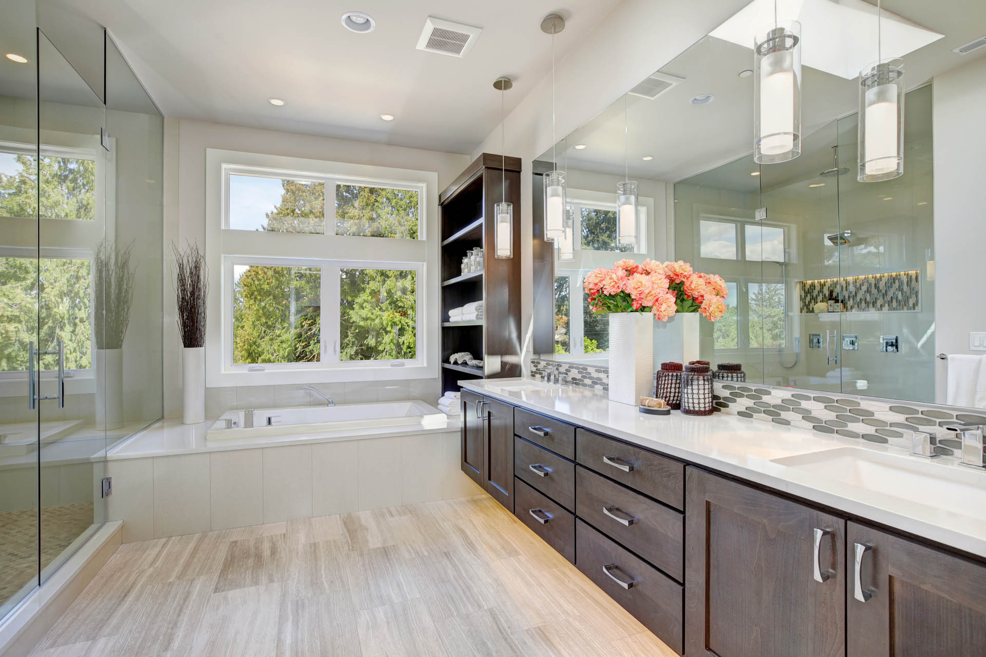 Contemporary master bathroom features a dark dual vanity cabinet glass walk-in shower drop-in tub and open cabinets filled with shelves.