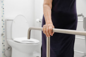 A senior woman using a guard rail in the bathroom