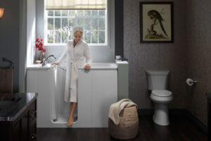 An older woman wearing a robe steps out of a walk-in tub