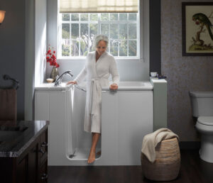 An older woman wearing a robe steps out of a walk-in tub