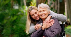 A younger woman embraces an older woman in a wheelchair